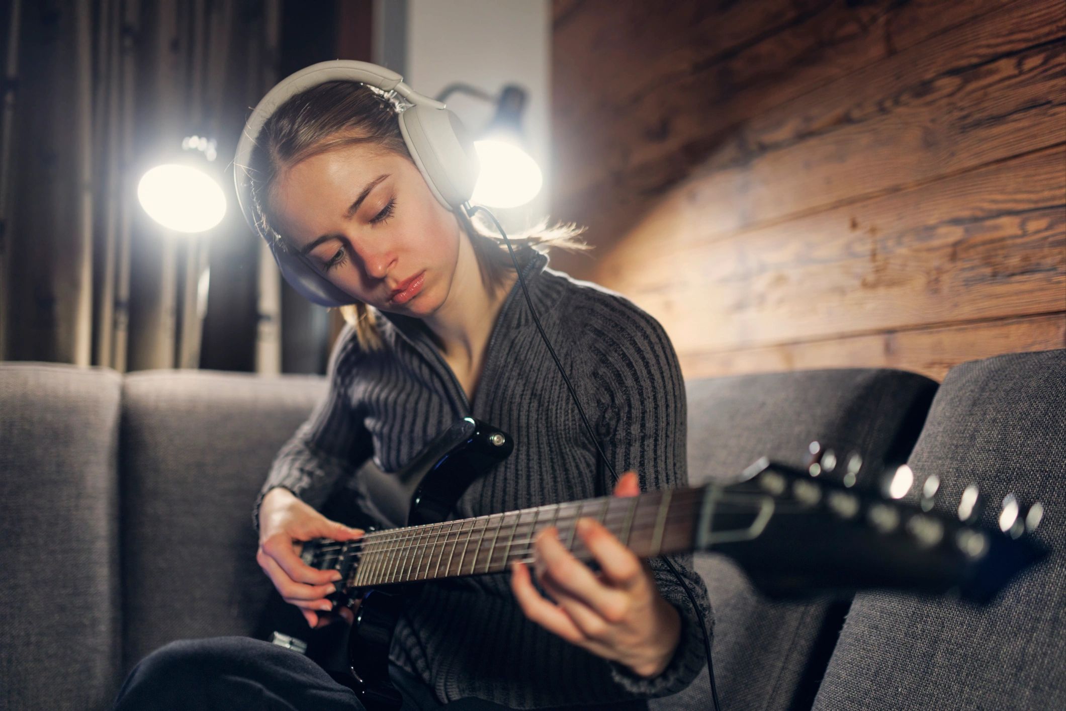 Young woman practicing playing electric guitar at home