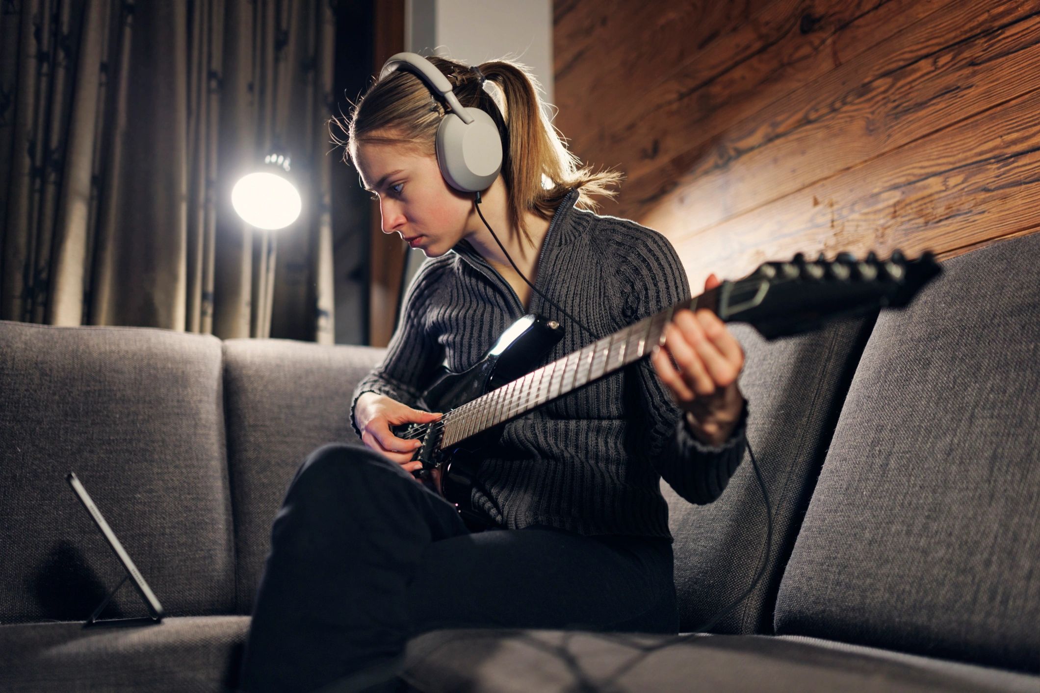 Young woman practicing playing electric guitar at home