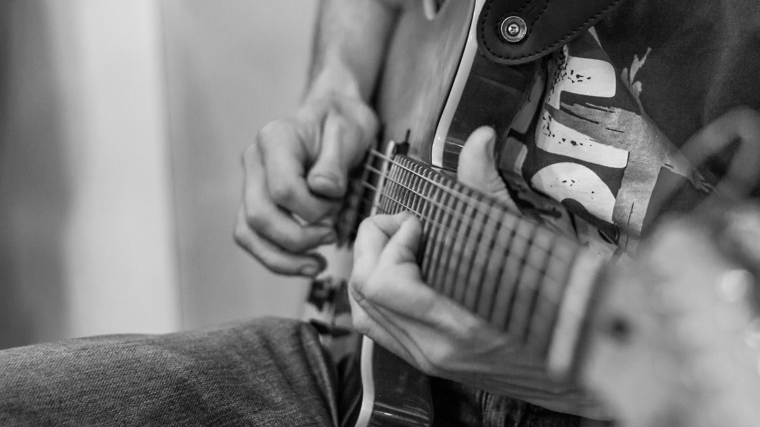 Mid adult man listening music and playing guitar lying down on floor